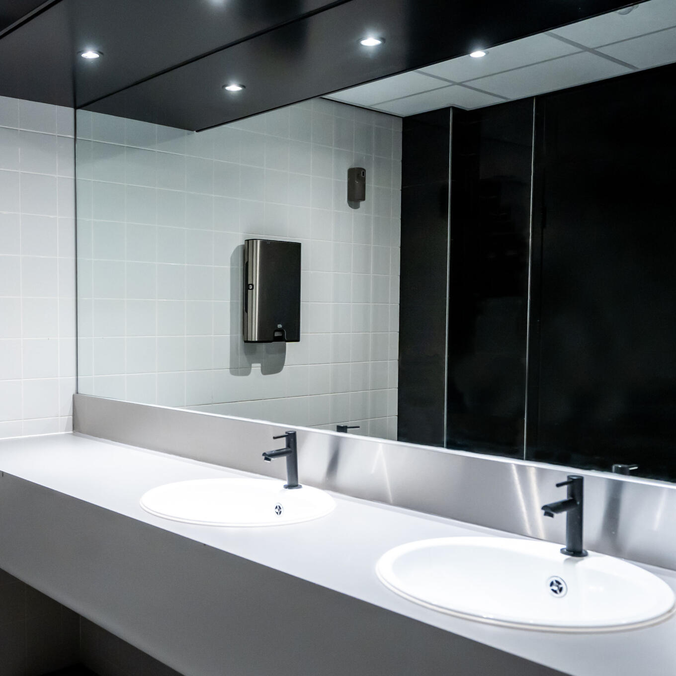 Grote wandspiegel bij een wastafel in een toiletruimte